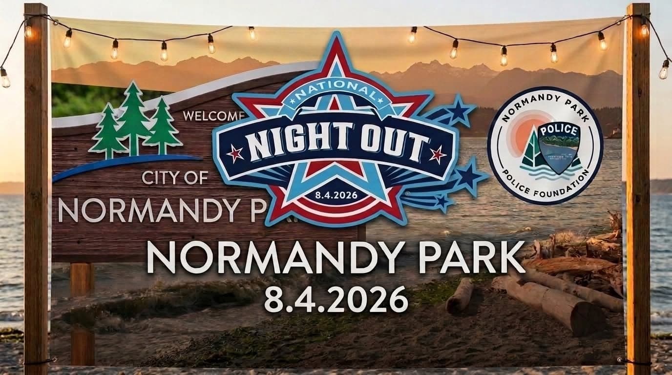 A National Night Out banner for Normandy Park dated August 4, 2026, with the Foundation's seal, hung between posts on a beach at sunset.