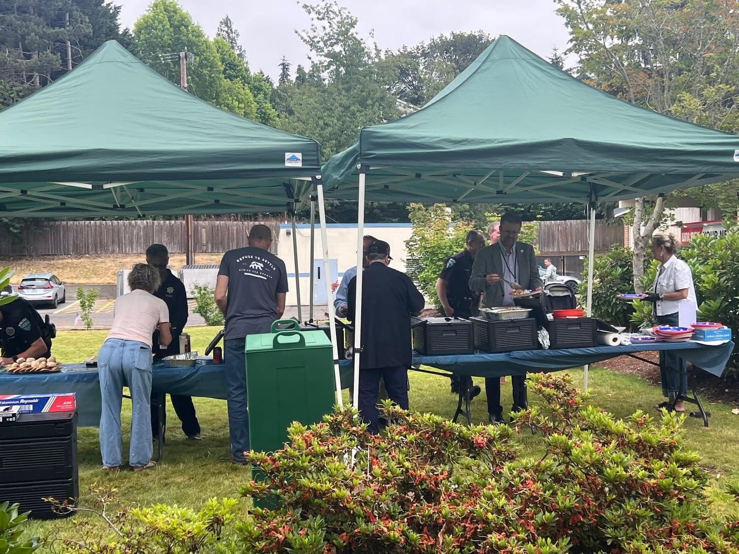 Guests in line at a buffet table under green canopy tents.